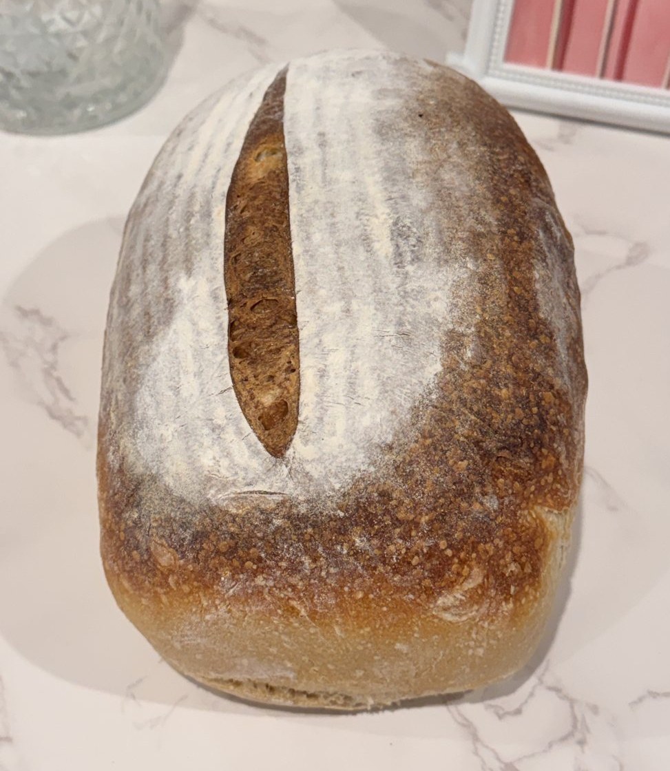 A fresh-baked artisan sourdough loaf, scored and flour-dusted